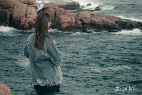 高清摄影 一位站在岩石海岸边的女性，她靠近大海。