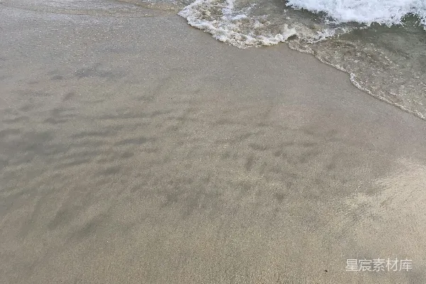 高清摄影 沙滩紧邻大海，海浪不断涌来。