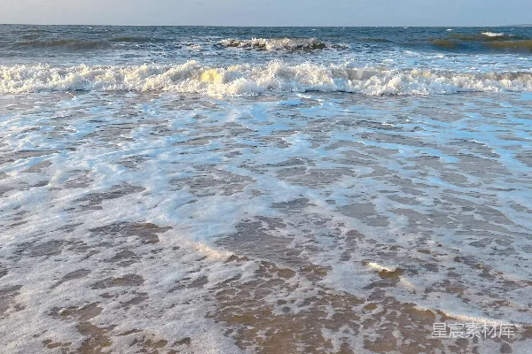 高清摄影 一个沙滩上，海浪拍打着岸边。