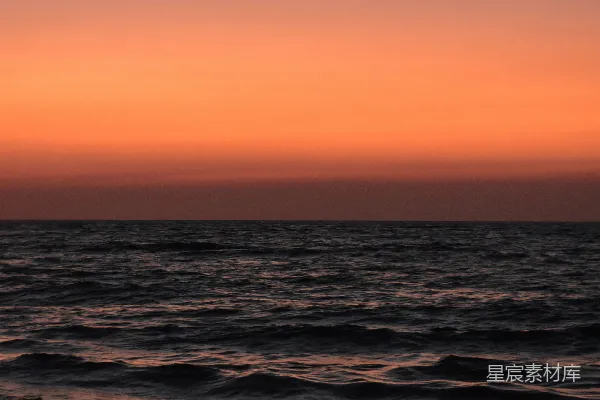 高清摄影 在色彩斑斓的橙色夕阳下，海浪轻轻拍打。