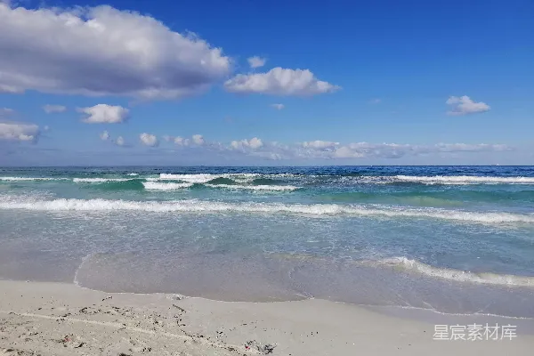 高清摄影 白天，蓝天白云下，海浪拍打着海岸。