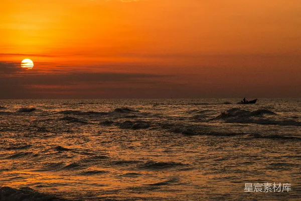 高清摄影 夕阳正缓缓落下，海面上有一艘小船。