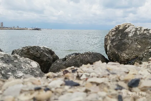 高清摄影 一块岩石海滩，背景中有一片水域。
