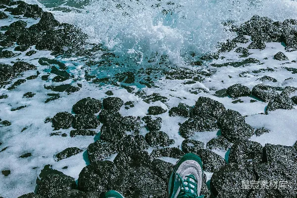 高清摄影 穿着绿色和白色运动鞋的人站在白天的岩石岸边。