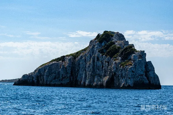 高清摄影 在蓝天下的白天，海中有一处棕色和绿色相间的岩石形成。