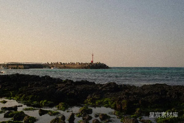 高清摄影 一个岩石海滩，远处有一座灯塔。
