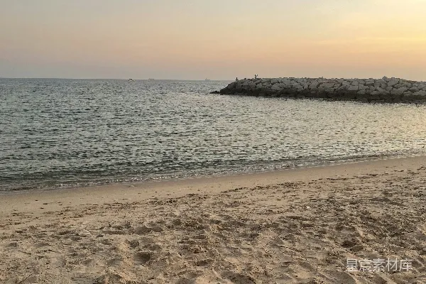 高清摄影 一片沙滩，背景中有一片水域。
