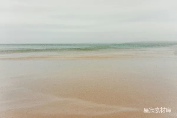 高清摄影 一张模糊的海滩照片，远处有一艘船。