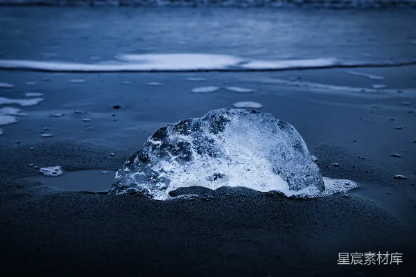 高清摄影 一座冰山停在沙滩上，背景中有水。