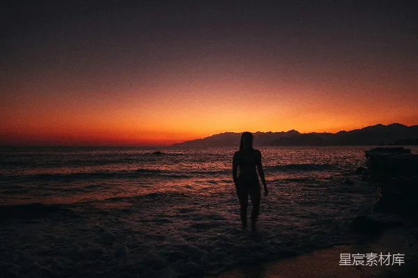 高清摄影 一对男女站在海滩上，夕阳下剪影。