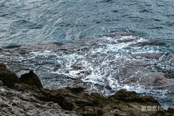 高清摄影 一个男人站在岩石海岸边，旁边是海洋。