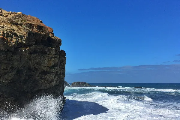 高清摄影 蓝天下的白天，海面上有棕色岩石形成物。
