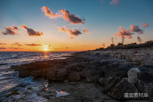 高清摄影 夕阳正缓缓落下，照耀着岩石海岸。