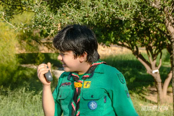 高清摄影 一个穿着绿色制服的男孩拿着一部手机。