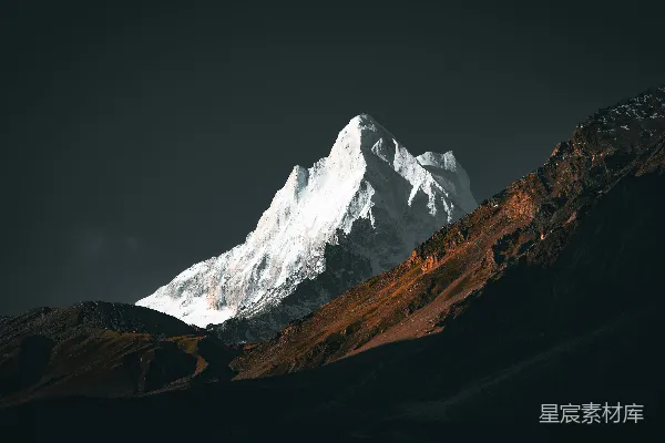 高清摄影 一座覆盖着积雪的山峰，背景是阴沉的天空。