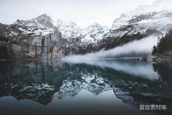 高清摄影 白天，水面上映照着被雪覆盖的山。
