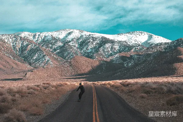 高清摄影 白天，一条棕色的土路旁覆盖着积雪的山。