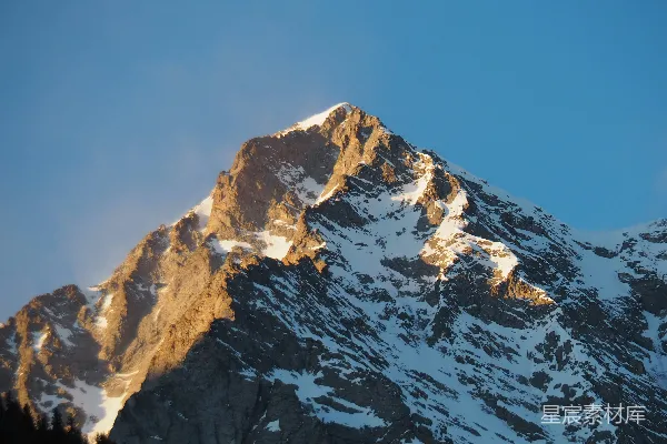 高清摄影 一座被雪覆盖的山峰，背景是蓝天。
