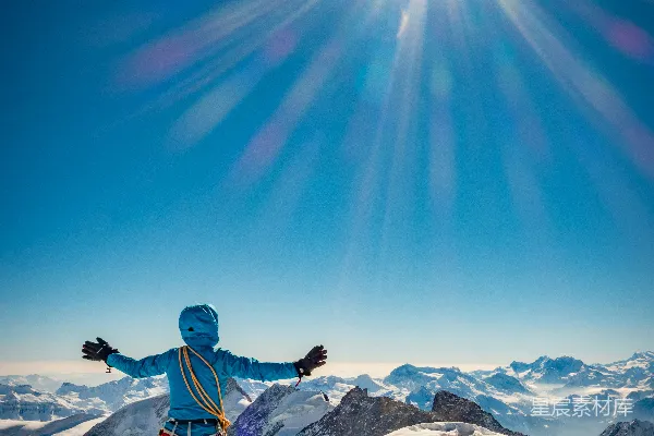 高清摄影 蓝衣黑裤的男人站在覆盖着积雪的山峰上，背景是蓝天。