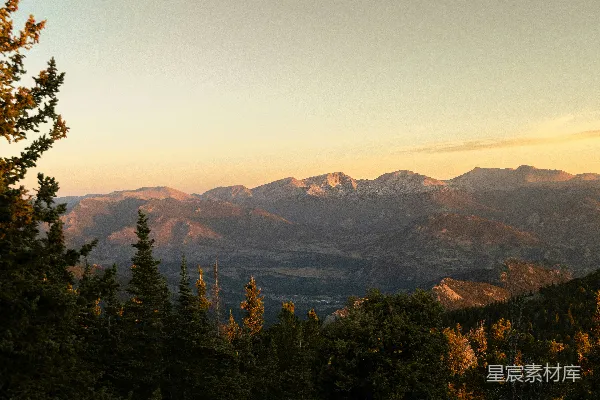 高清摄影 夕阳下的山脉，前景是松树