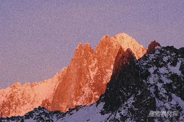 高清摄影 一座被雪覆盖的山峰，背景是粉红色的天空。