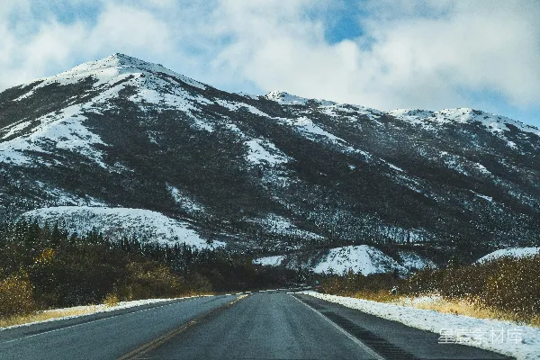 高清摄影 一座覆盖着积雪的山脉，一条道路穿过其中。