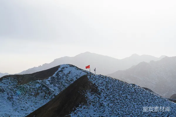 高清摄影 一座覆盖着积雪的山顶上插着一面红旗