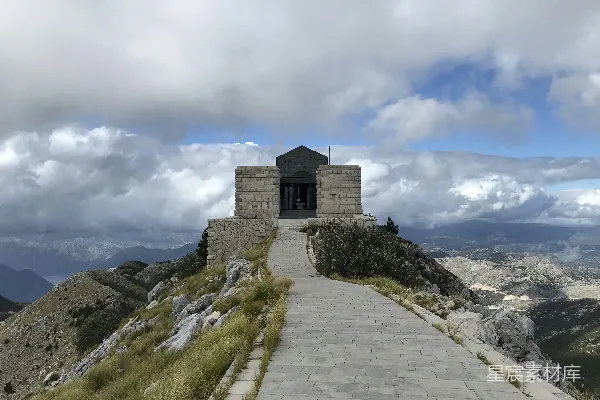 高清摄影 白天，多云的天空下，一座灰色的混凝土建筑位于山丘之巅。