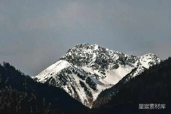 高清摄影 一座被雪覆盖的山在阴云密布的天空下