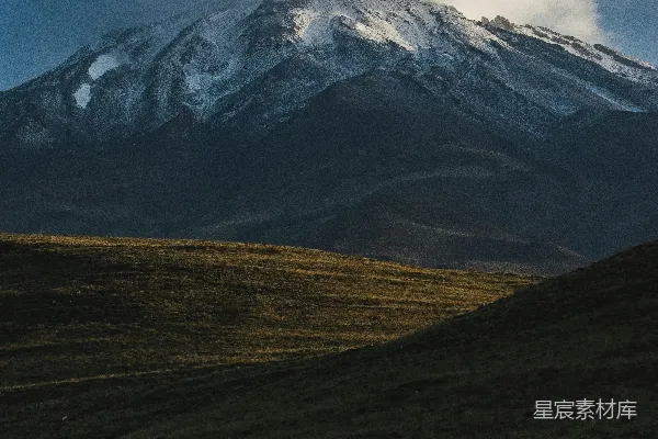 高清摄影 一个人站在田野里，背景是山脉。