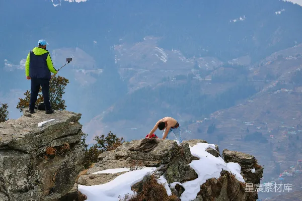 高清摄影 一个男人站在山顶上，旁边是被雪覆盖的岩石。