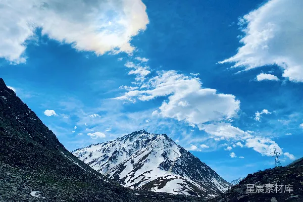 高清摄影 一座被雪覆盖的山峰在多云的蓝天之下