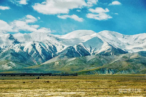 高清摄影 一辆火车穿越乡村，背景是群山。