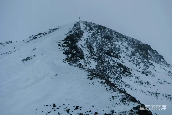 高清摄影 一座被雪覆盖的山峰，一个人站在山顶上。