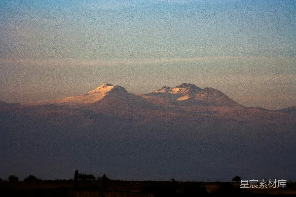 高清摄影 夕阳下白雪覆盖的山峰，隐约可见轮廓。