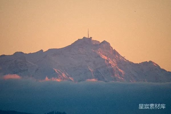 高清摄影 夕阳西下，雪山顶上矗立着一座无线电塔。