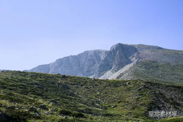 高清摄影 一座山脉，山脚下有一片草地。