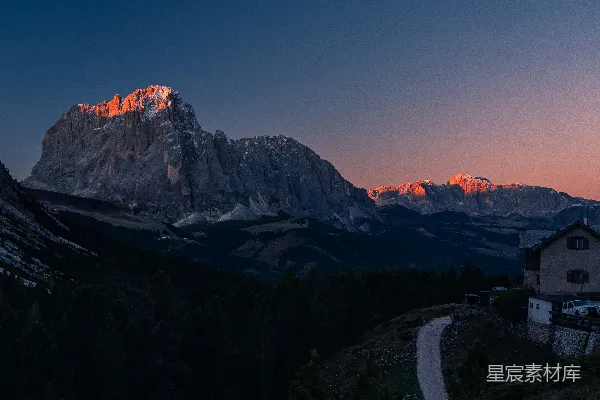 高清摄影 夕阳下，山峰闪闪发光，旁边有一座建筑物。