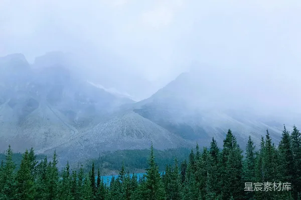 高清摄影 云雾缭绕的群山矗立在一片绿色树林之上。