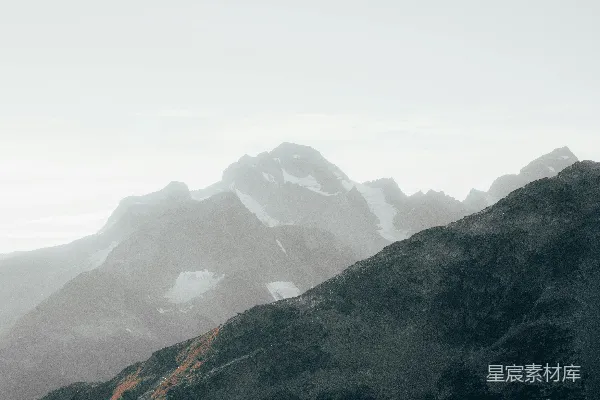 高清摄影 远处覆盖着积雪的山峦在雾气中若隐若现。
