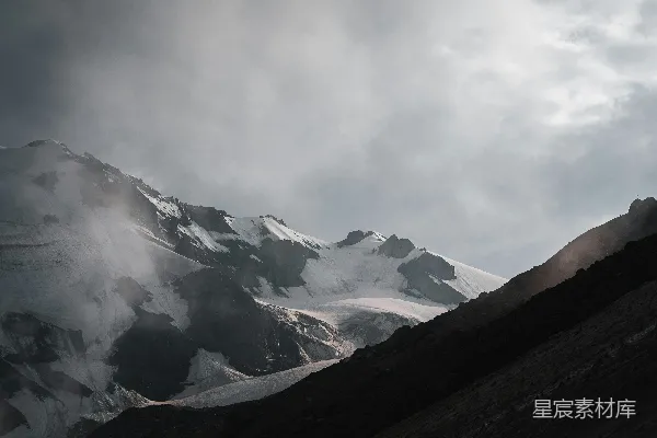 高清摄影 云层密布的天空下覆盖着积雪的山峰