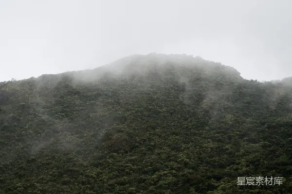 高清摄影 一座高耸入云的山峰，笼罩在雾气和云层之中。