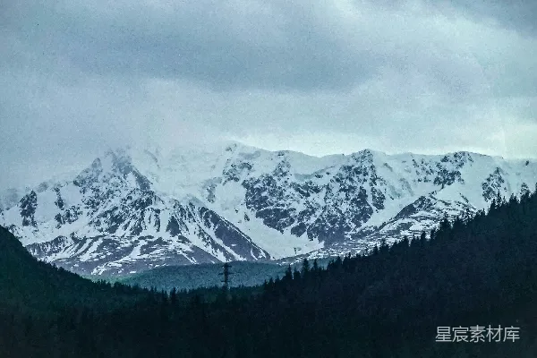 高清摄影 连绵的雪山覆盖着皑皑白雪，在阴云密布的天空下显得格外壮丽。
