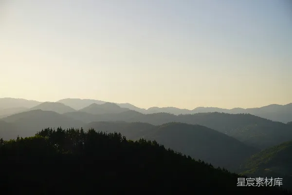高清摄影 一片山峦景色，前景中有树木。