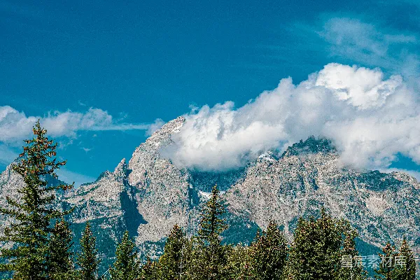 高清摄影 一座山脉，前景是树木，背景是云层。