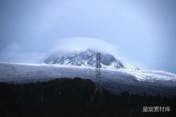 高清摄影 一座覆盖着积雪的山，前景中有一根电线杆。