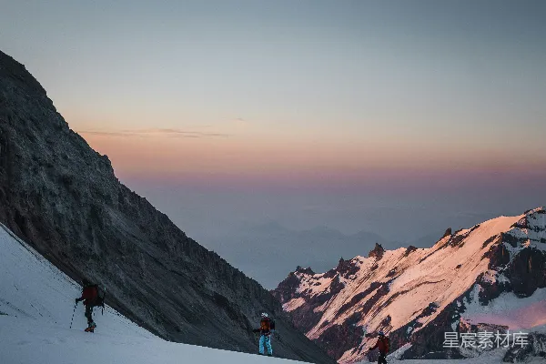 高清摄影 一群人在积雪覆盖的山侧徒步登山。