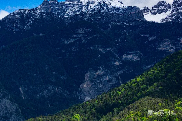 高清摄影 白雪覆盖的山峰高耸于生机勃勃的绿林之上。