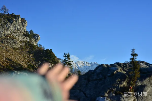 高清摄影 一只手伸向背景是蓝天的山峰。