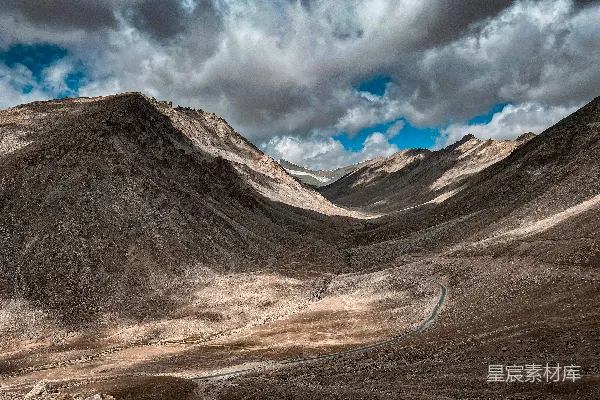 高清摄影 一条蜿蜒的道路在前景中，山峦绵延。